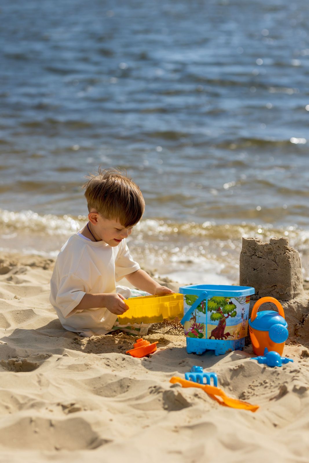 Kind spielt mit Sandspielzeug am Ufer