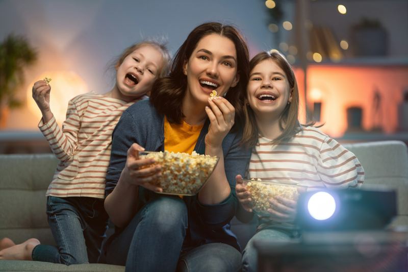 Kinder mit Popcorn beim gemütlichen Filmabend vor dem Beamer